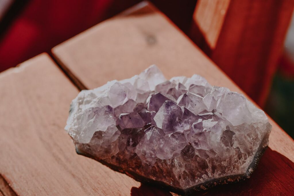 Detailed close-up of a raw amethyst crystal on a wooden surface.